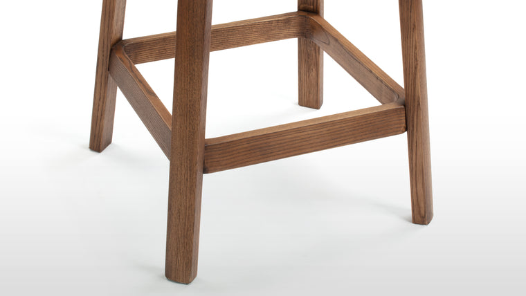 Timeless Design | The stool's solid wood frame, inspired by the timeless designs of Pierre Jeanneret, boasts clean lines and a rich finish that perfectly complements the rattan seat. The angled legs provide stability while adding a hint of architectural interest to the overall aesthetic.
