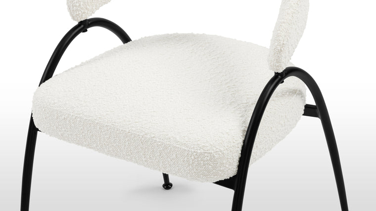 Light Design, Bold Impact | The black metal frame offers a stark contrast to the plush white boucle upholstery, enhancing the chair's visual appeal. The slender legs of the chair contribute to its modern look, emphasizing clean lines and an airy feel.
