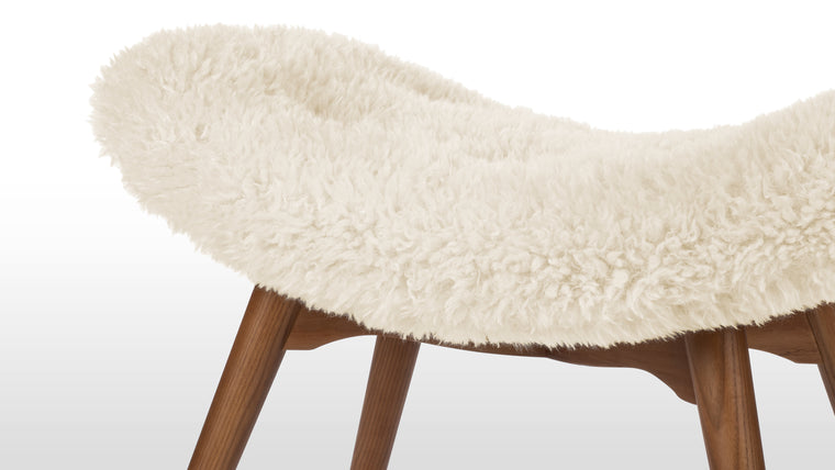 Plush Meets Wood | The footstool's materials offer a tactile contrast, with fluffy faux fur fabric embracing the main body, while warm wooden legs provide sturdy support. This mix of textures adds depth and warmth to any room.
